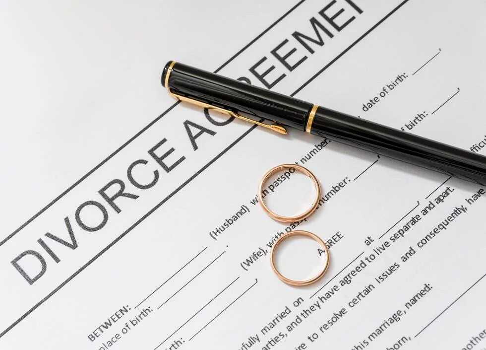 Divorce agreement form with wedding rings and a pen, illustrating finality in family law cases.