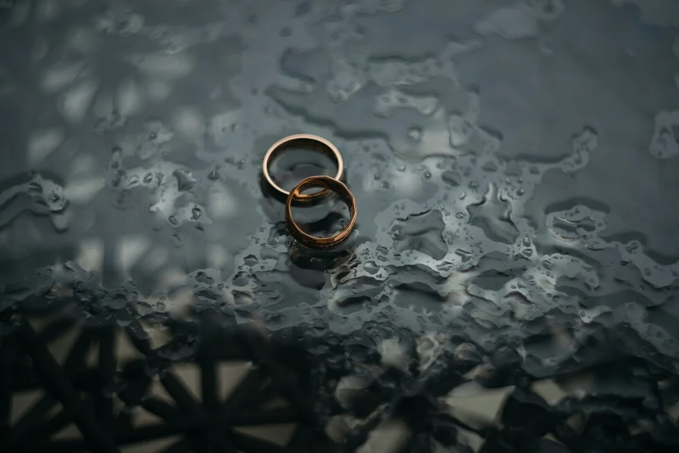 Wedding rings on a dark surface representing complex immigration and divorce legal issues.