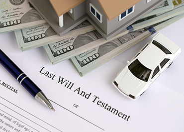 Cash, model house, and car on a Last Will and Testament for estate planning.